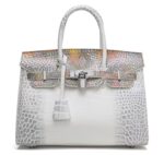 White crocodile embossed luxury handbag with multicolor painted flap and silver padlock closure, structured satchel with top handle on white background